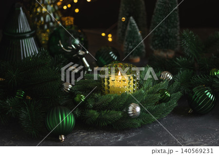Christmas eve decorating with burning candle and green ornaments 140569231