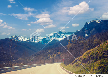 View of beautiful mountain landscape through the windscreen on a sunny day. Driving a car on mountain winding road in National park Picos de Europa. Cantabria, Spain, Europe View of beautiful mountain landscape through the windscreen on a sunny day. Driving a car on mountain winding road in National park Picos de Europa. Cantabria, Spain, Europe 140569579