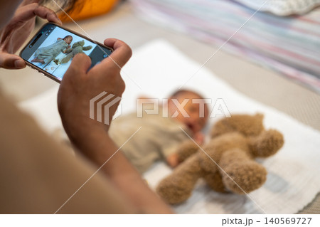 スマホで赤ちゃんの写真を撮っている新米 スマホで赤ちゃんの写真を撮っている新米 140569727