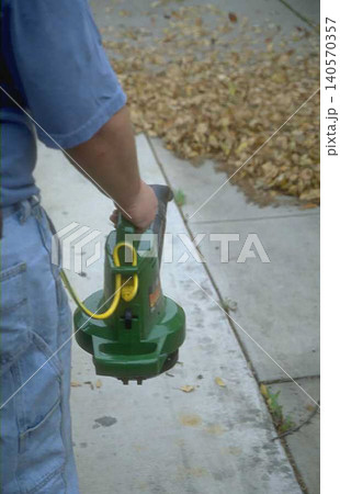 a Person Operating Green Leaf Blower on Concrete Surface a Person Operating Green Leaf Blower on Concrete Surface 140570357