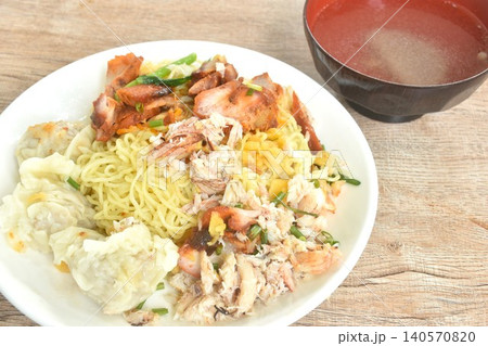 dry Chinese egg yellow noodles with red barbecue pork and dumpling topping crab meat on plate with clear soup cup dry Chinese egg yellow noodles with red barbecue pork and dumpling topping crab meat on plate with clear soup cup 140570820