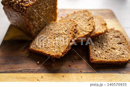 Whole grain seeded bread loaf with sliced pieces on wooden board under natural light Whole grain seeded bread loaf with sliced pieces on wooden board under natural light 140570935