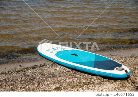 Stand up paddle board on the shore by the water during sunny weather 140571652