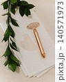 Facial rose quartz stone massage roller and gua sha massager on a white towel background. 140571973