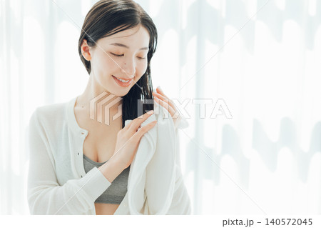 濡れた髪の毛をタオルで拭く若い女性 濡れた髪の毛をタオルで拭く若い女性 140572045