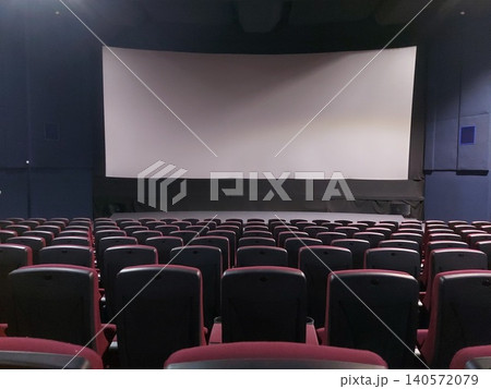 An empty cinema before a movie screening. White screen in front of empty cinema seats. An empty cinema before a movie screening. White screen in front of empty cinema seats. 140572079