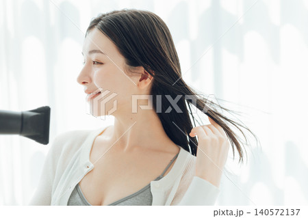 濡れた髪の毛をドライヤーで乾かす若い女性 140572137