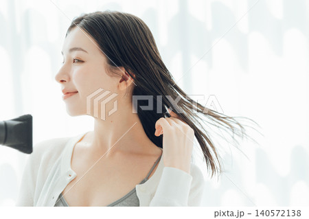 濡れた髪の毛をドライヤーで乾かす若い女性 濡れた髪の毛をドライヤーで乾かす若い女性 140572138