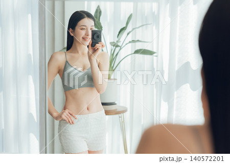 鍛えた体を鏡越しに自撮りをする女性 鍛えた体を鏡越しに自撮りをする女性 140572201