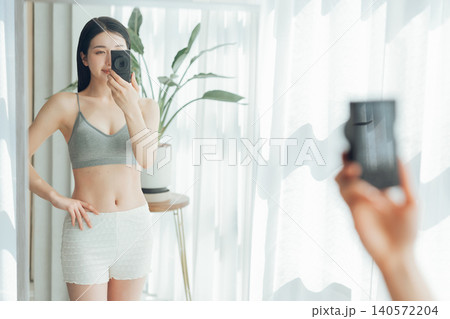 鍛えた体を鏡越しに自撮りをする女性 140572204