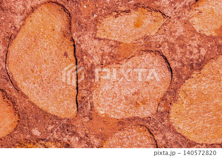 Macro horizontal shot of an ancient textured rock wall with a warm terracotta tint, highlighting rough flagstone masonry and organic gritty concrete filler details Macro horizontal shot of an ancient textured rock wall with a warm terracotta tint, highlighting rough flagstone masonry and organic gritty concrete filler details 140572820