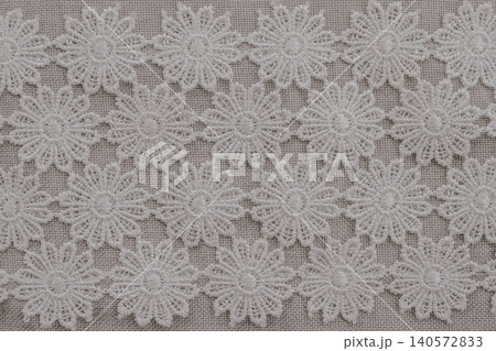 Top view full frame background of elegant white floral lace trimming ribbons laid in rows on a gray linen fabric canvas, perfect for rustic or wedding handcraft Top view full frame background of elegant white floral lace trimming ribbons laid in rows on a gray linen fabric canvas, perfect for rustic or wedding handcraft 140572833
