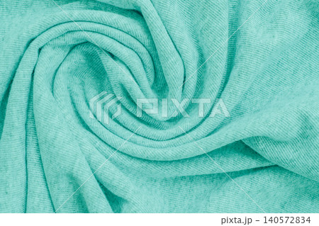 Top view full frame background of a soft turquoise knit fabric texture swirled into a spiral pattern, showcasing gentle folds and cozy ribbed textile lines Top view full frame background of a soft turquoise knit fabric texture swirled into a spiral pattern, showcasing gentle folds and cozy ribbed textile lines 140572834