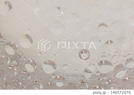 Top up abstract view of clean water drops and condensation steam on a transparent glass surface, creating a bright warm bubble texture backdrop or template Top up abstract view of clean water drops and condensation steam on a transparent glass surface, creating a bright warm bubble texture backdrop or template 140572878