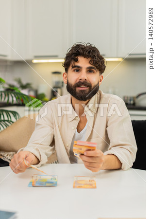 Indian man counting euro cash savings in neat stacks planning budget dreaming about future purchase Indian man counting euro cash savings in neat stacks planning budget dreaming about future purchase 140572989