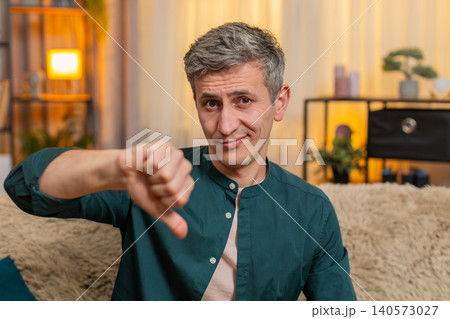 Young man shows thumbs down gesture with serious expression showing disapproval or disagreement Young man shows thumbs down gesture with serious expression showing disapproval or disagreement 140573027