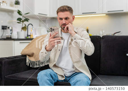 Young man loses game on smartphone sighs in defeat shows sad reaction disappointed mood after error 140573150