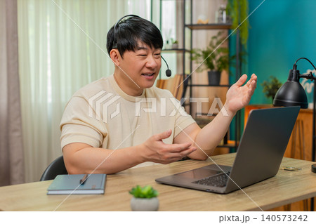 Asian man on laptop headset video call, giving live support with calm tone, online customer service Asian man on laptop headset video call, giving live support with calm tone, online customer service 140573242