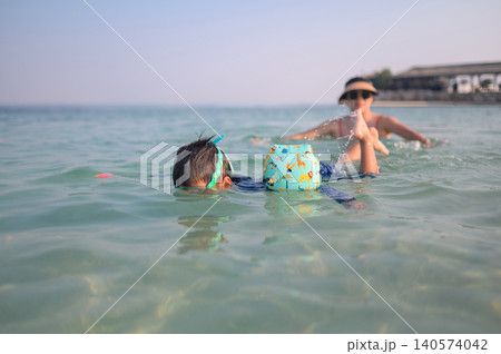 Child Swimming with Mother in Clear Water at Beach on Sunny Day Child Swimming with Mother in Clear Water at Beach on Sunny Day 140574042