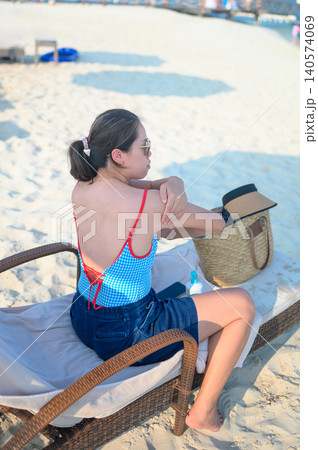 Asian Woman in Her 30s Relaxing on Beach Lounger in Stylish Swim Asian Woman in Her 30s Relaxing on Beach Lounger in Stylish Swim 140574069