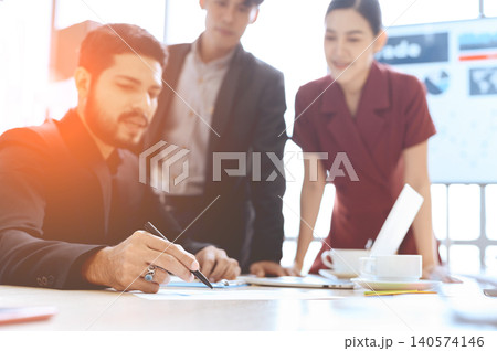 Businessman pointing pen to analytical reports document in meeting with colleagues. Select focus to pen in his hand. 140574146