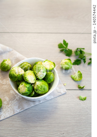 raw brussels sprouts in white bowl on wooden background raw brussels sprouts in white bowl on wooden background 140574442