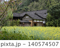 A house with a dark tiled roof in a rapeseed field in the mountains near Zhangjiajie, China 140574507