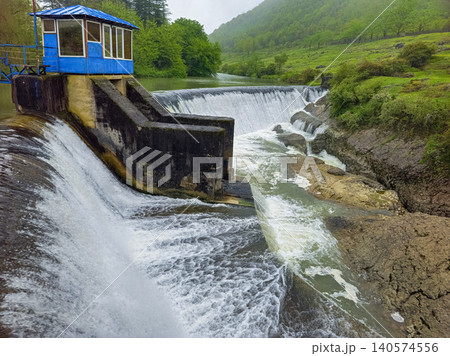 Rugged waterfall cascades over stone dam structure 140574556
