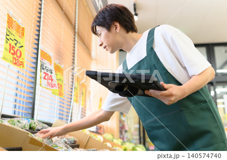 スーパーで端末を操作する男性店員 スーパーで端末を操作する男性店員 140574740