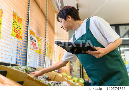 端末を持ち野菜をチェックする店員 140574753