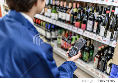 酒類棚の商品を端末で確認する店員 140574765
