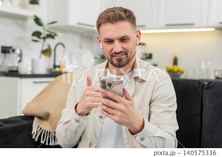 Young man studies online course on smartphone uses headphones listens lecture and sets weekly goal Young man studies online course on smartphone uses headphones listens lecture and sets weekly goal 140575336