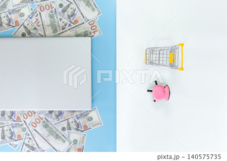 Bright cash scattered beside a tablet. Tiny shopping cart beside a pink piggy bank. Clean, minimal background. Ideal for finance, savings, or shopping concepts. Simple, cheerful, modern aesthetic Bright cash scattered beside a tablet. Tiny shopping cart beside a pink piggy bank. Clean, minimal background. Ideal for finance, savings, or shopping concepts. Simple, cheerful, modern aesthetic 140575735