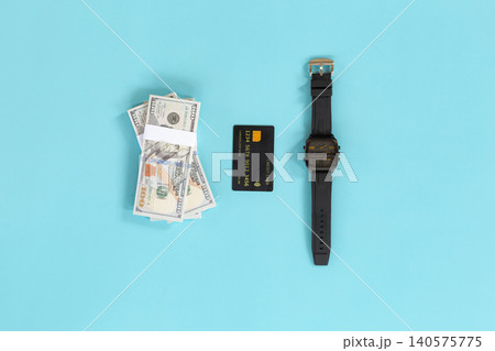 Money, card, and watch lie on bright blue background. No people, no animals, no plants present. Clean, minimalist setup suggests financial success or time management. Ideal for business, finance Money, card, and watch lie on bright blue background. No people, no animals, no plants present. Clean, minimalist setup suggests financial success or time management. Ideal for business, finance 140575775