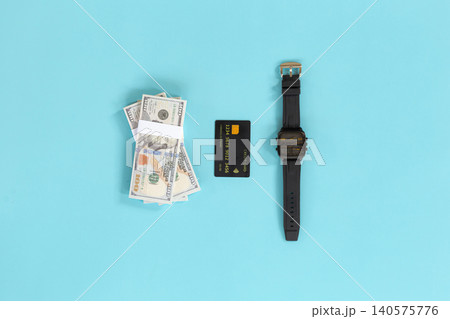 Money, card, and watch lie on bright blue background. No people, no animals, no plants present. Clean, minimalist setup suggests financial success or time management. Ideal for business, finance Money, card, and watch lie on bright blue background. No people, no animals, no plants present. Clean, minimalist setup suggests financial success or time management. Ideal for business, finance 140575776