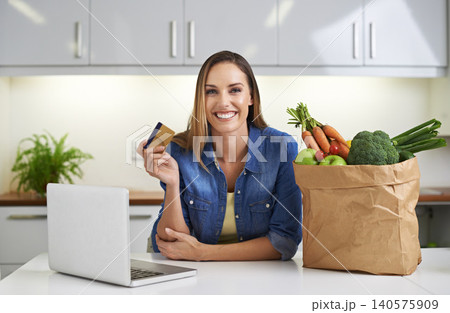 Happy woman, laptop and credit card with grocery bag for payment, online shopping or order in kitchen at home. Portrait of female person with smile, computer or debit in purchase or delivery at house 140575909