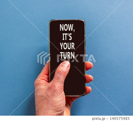 Now it's your turn symbol. Concept words Now it's your turn on beautiful phone screen. Beautiful blue background. Businessman hand. Business Now it's your turn motivational support concept. Copy space 140575985