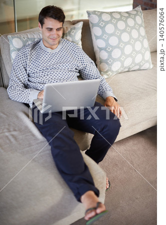 Relax, happy or man on laptop for download, article post or networking in home to research. Email, smile or male person on sofa typing online on technology for streaming, movie or news on website 140576064