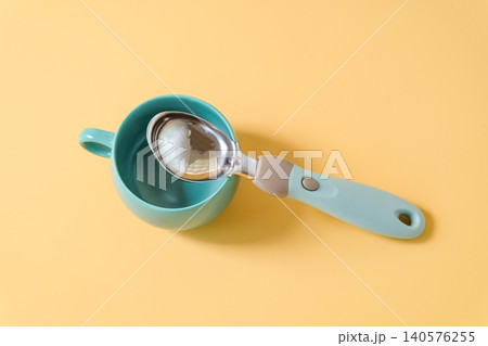 Ice-cream spoon with cup of coffee on background. Ice-cream spoon with cup of coffee on background. 140576255