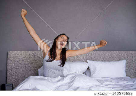 Woman, bedroom and wake up in morning with yawn for routine or fatigue, stretching and sleepy after rest. Female person, home and awake after sleep for wellness, energy and comfort for mental health. Woman, bedroom and wake up in morning with yawn for routine or fatigue, stretching and sleepy after rest. Female person, home and awake after sleep for wellness, energy and comfort for mental health. 140576688