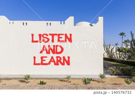 Listen and learn words symbol. Concept words Listen and learn on beautiful white wall. Beautiful blue sky background. Business listen and learn support concept. Copy space. 140576732