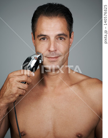 Man, portrait and shave with electric razor for hair removal grooming or beard maintenance, hygiene or grey background. Male person, face and tool for healthy self care in studio, mockup or skincare 140576825