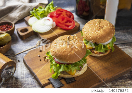 Two savory delicious homemade cheeseburger in kitchen gadget modern air fryer on wooden background. Lifestyle trendy of new cooking. 140576872