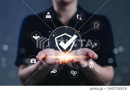 Work safety and compliance management concept. A person holds a shield check surrounded by safety, compliance, and risk assessment symbols, representing occupational health and workplace regulations. Work safety and compliance management concept. A person holds a shield check surrounded by safety, compliance, and risk assessment symbols, representing occupational health and workplace regulations. 140576919
