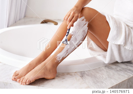 Woman, legs and hair removal in bathroom with shaving for skincare, body wellness and morning routine in home. Person, razor and cream for grooming, hygiene and pamper for self care and cleaning Woman, legs and hair removal in bathroom with shaving for skincare, body wellness and morning routine in home. Person, razor and cream for grooming, hygiene and pamper for self care and cleaning 140576971