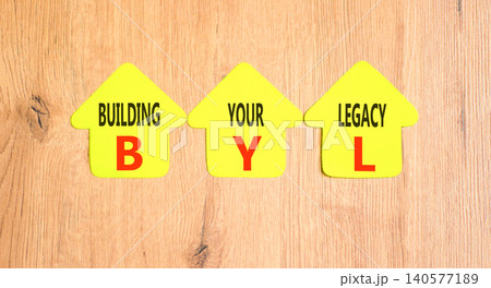 BYL building your legacy symbol. Concept words BYL building your legacy on beautiful yellow paper houses. Beautiful wooden background. Business BYL building your legacy concept. Copy space. BYL building your legacy symbol. Concept words BYL building your legacy on beautiful yellow paper houses. Beautiful wooden background. Business BYL building your legacy concept. Copy space. 140577189