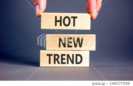 Hot new trend words symbol. Concept words Hot new trend on beautiful wooden blocks. Beautiful grey background. Businessman hand. Business and hot new trend concept. Copy space. Hot new trend words symbol. Concept words Hot new trend on beautiful wooden blocks. Beautiful grey background. Businessman hand. Business and hot new trend concept. Copy space. 140577399