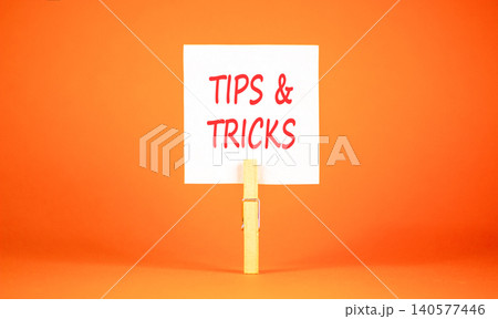 Tips and tricks words symbol. Concept words Tips and tricks on beautiful white paper on wooden clothespin. Beautiful orange background. Business tips and tricks motivational support concept Copy space Tips and tricks words symbol. Concept words Tips and tricks on beautiful white paper on wooden clothespin. Beautiful orange background. Business tips and tricks motivational support concept Copy space 140577446