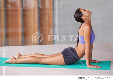 Woman, yoga and stretching with mat for workout, exercise or pilates in cobra pose at home. Female person or yogi in body warm up or training for awareness, health and wellness or fitness on floor 140577672