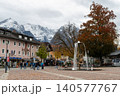 GARMISCH-PARTENKIRCHEN, GERMANY - OCTOBER 25, 2025: People move through a town square with a fountain, autumn trees, shops, and snowy mountain scenery in Garmisch-Partenkirchen, Bavaria. 140577767